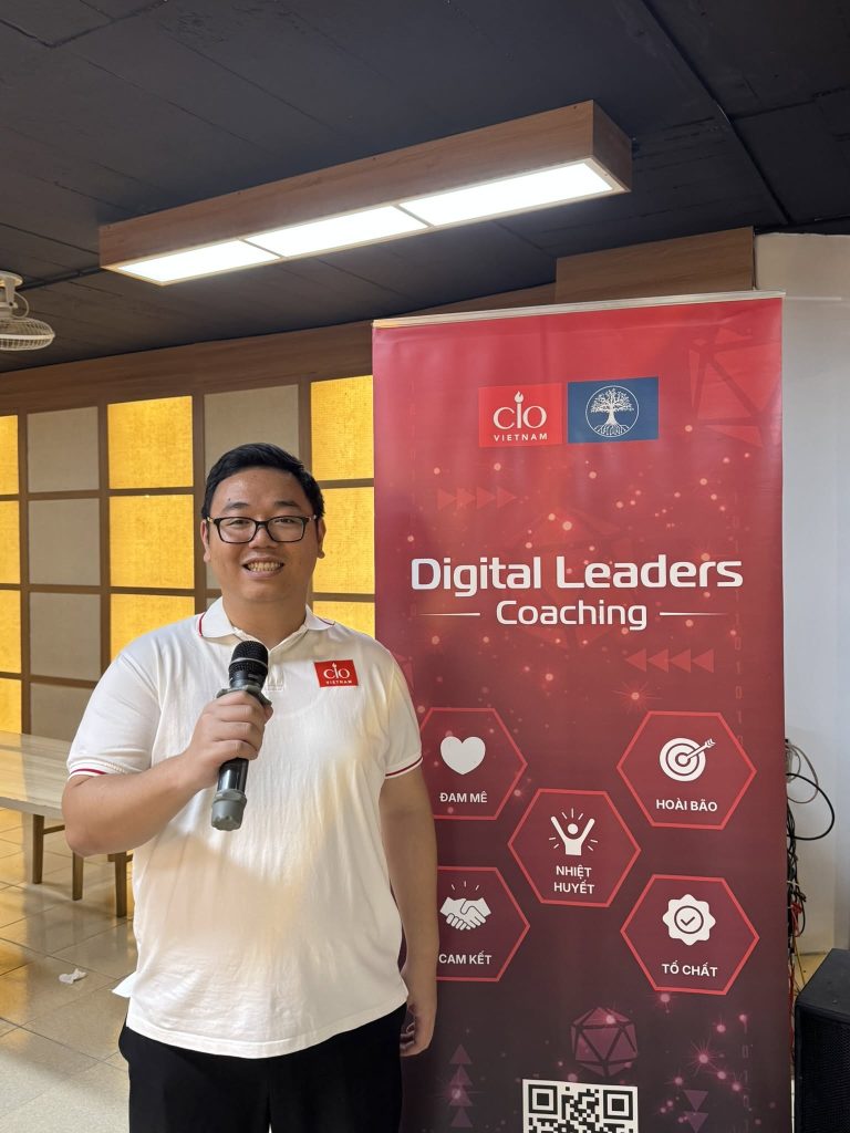 Enterprise Data Management: khi câu hỏi về dữ liệu không còn bắt đầu từ công nghệ 6 Học viên cầm micro chia sẻ bên cạnh standee Digital Leaders Coaching