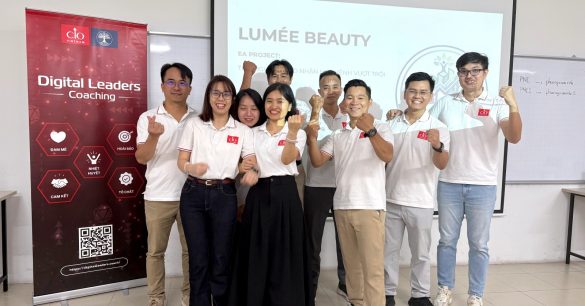 Nhóm học viên Digital Leaders Coaching SS10 TP.HCM giơ tay chào trước màn chiếu dự án EA Lumée Beauty, bên standee chương trình