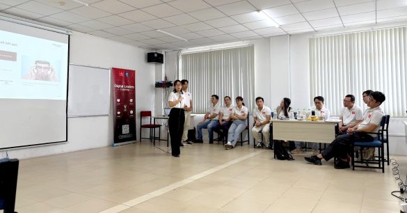 Một học viên Digital Leaders Coaching SS10 TP.HCM cầm micro trình bày trước lớp, các bạn khác ngồi lắng nghe