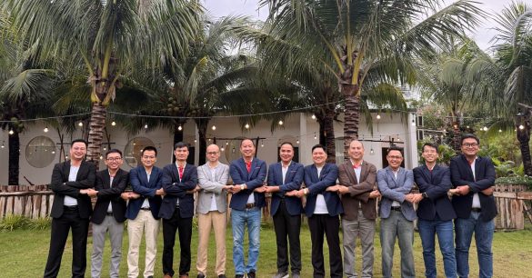 Ban huấn luyện Digital Leaders Coaching nắm tay nhau thành hàng ngoài trời trong chuyến team building của ban huấn luyện